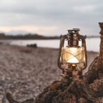 Campinglampe auf einer Baumwurzel am Meer
