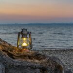 Campinglampe auf einer Baumwurzel am Meer